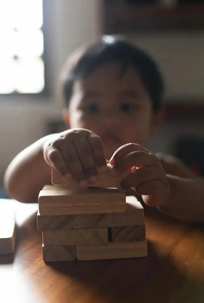 A toddler carefully balancing flat wooden blocks