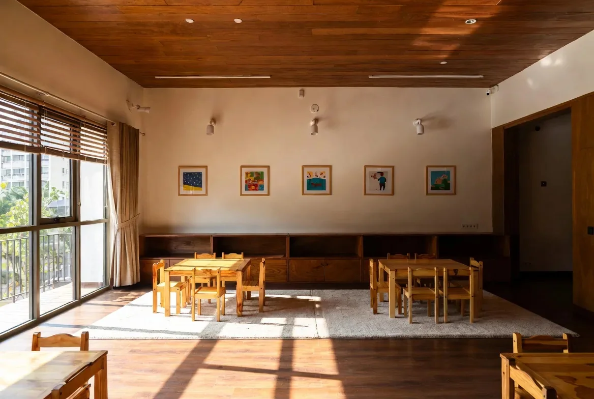An empty classroom with low tables and children's artwork on the wall