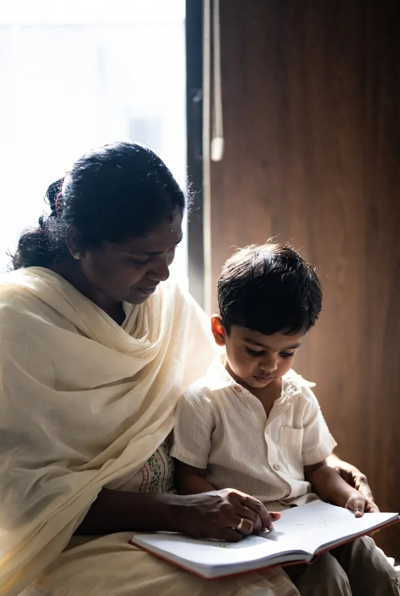 An adult and child looking closely at a picture book together