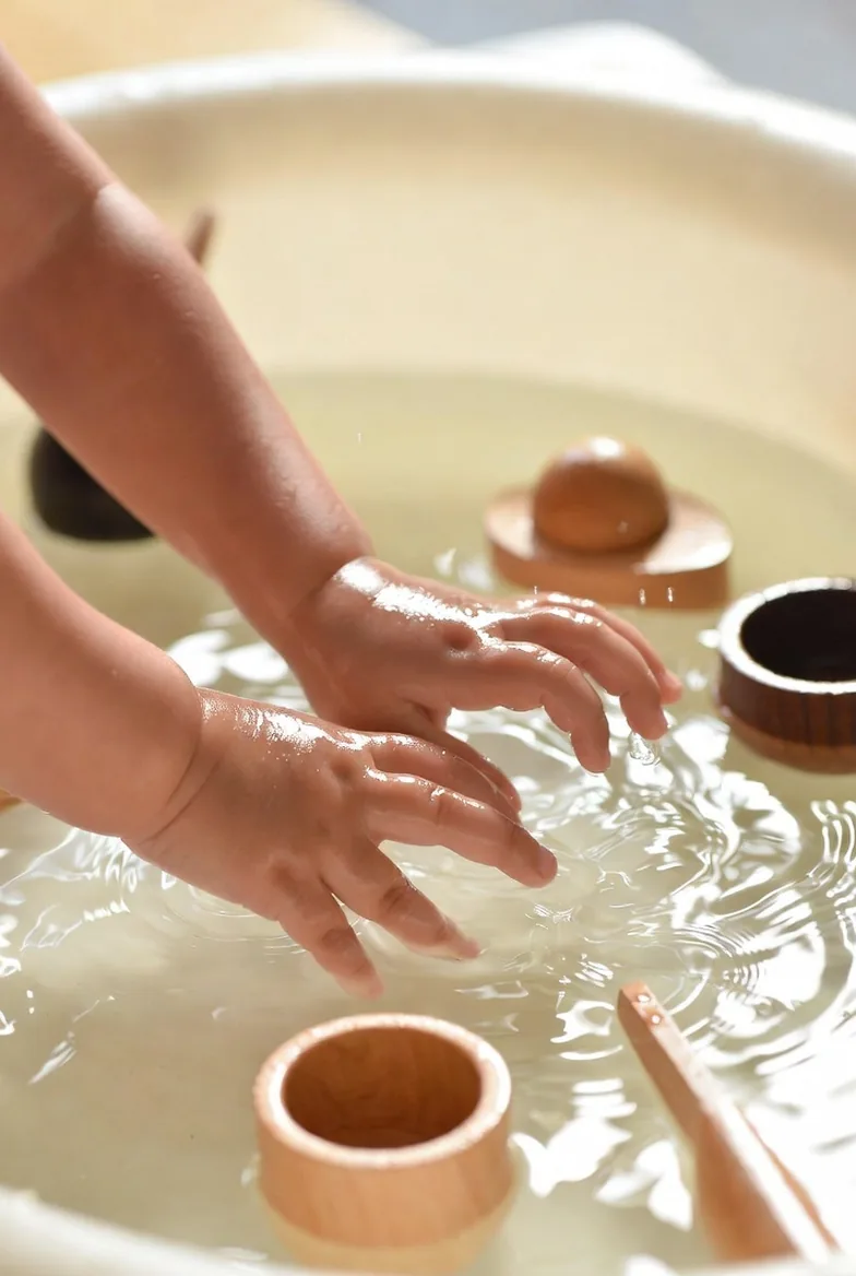Two small hands resting in a basin of water